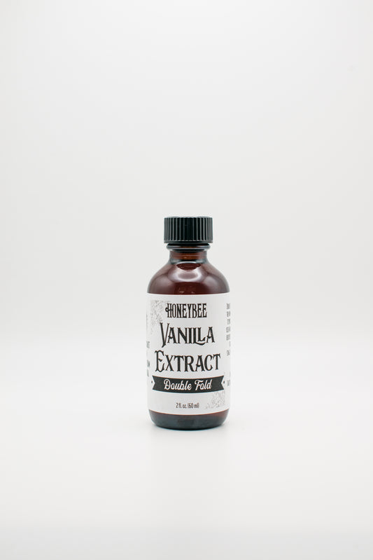 A 4-ounce dark amber bottle with a black cap, labeled "Honeybee Vanilla Extract (Double Fold)". The label is white with black text, and the bottle is placed on a plain white background. Professional bakers love its richer vanilla flavor for creating exceptional desserts.